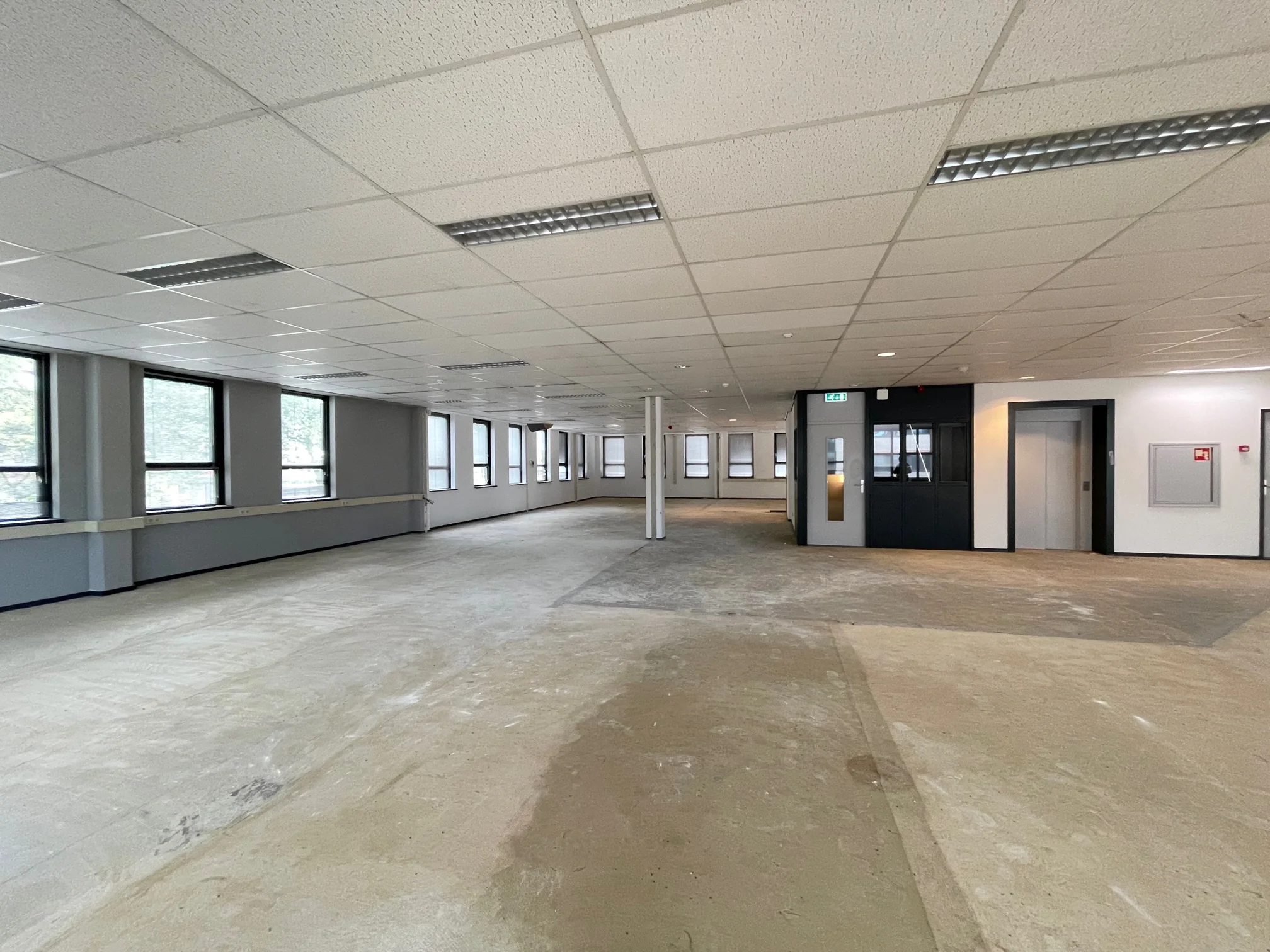 Leeg kantoorpand aan de Rivium 4e Straat met systeemplafond, grote ramen en een lift.